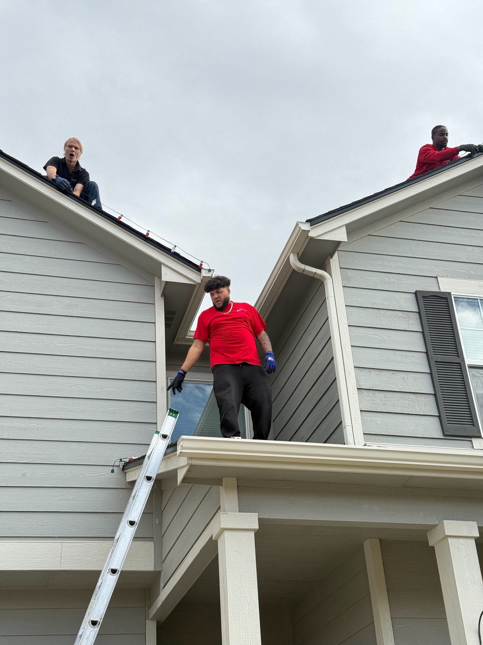 Our Front Range team installing multicolor Christmas lights along roof peaks