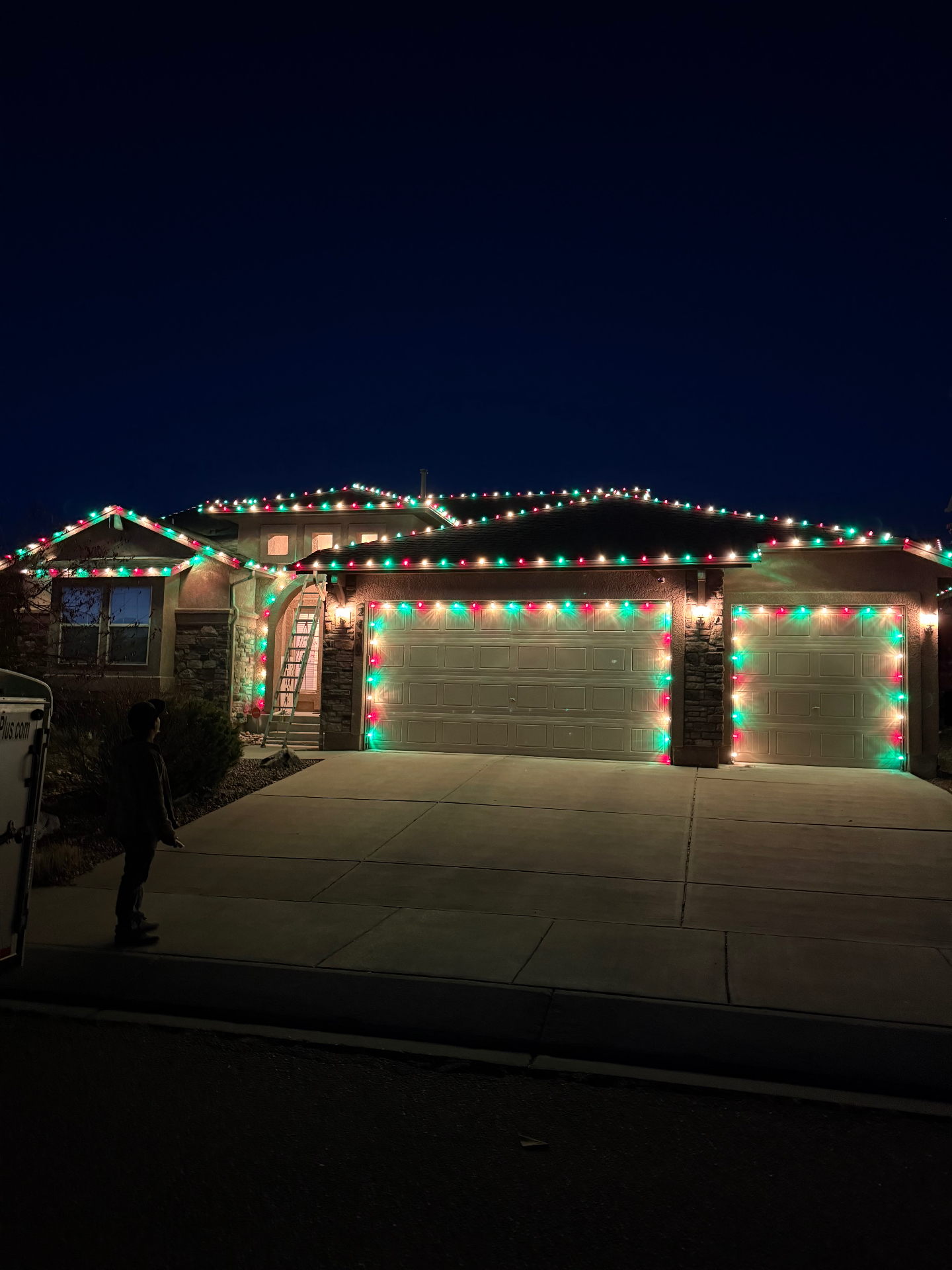 Red and green residential Christmas light installation across a home's roofline and garage, Front Range portfolio